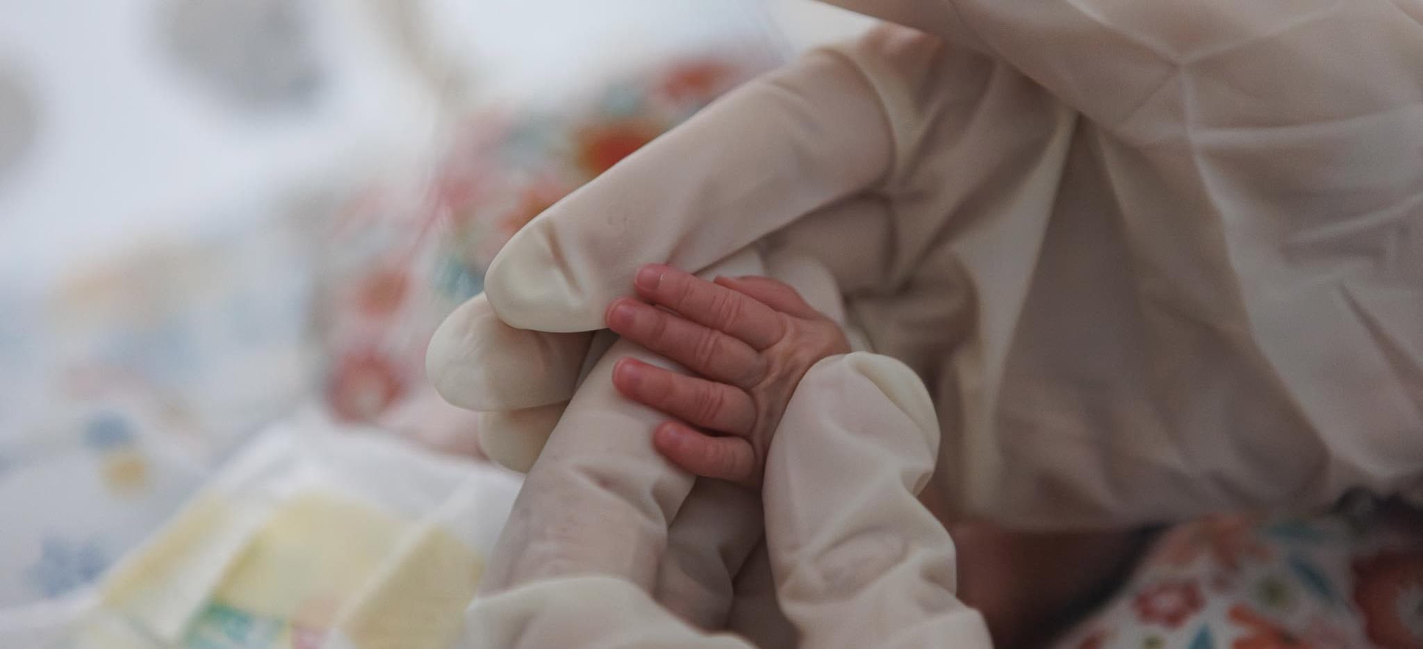 Новорожденный малыш держит палец врача - ведение беременности в Краснодаре